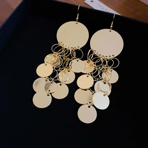 Detail of gold fringe earrings with circular sequins in a black gift box with a card