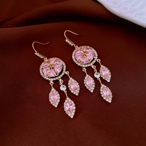Detail of pink crystal tassel earrings with gold-toned hooks on silk background