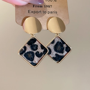 Detail of gold rhombus earrings with leopard print plush texture and fuzzy finish