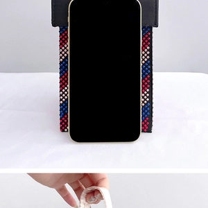 Detail of a black leather rhinestone mini bag with red and blue crystals for evening use