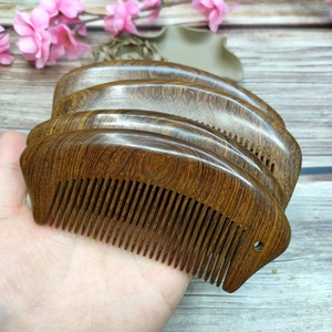 Close-up of stackable fish-shaped sandalwood hair combs with natural wood grain
