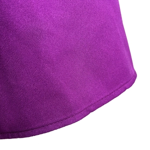 Close-up of purple textured fabric with precise rolled hem stitching on the dress