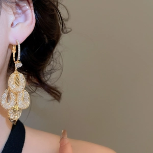 Detailed view of gold tassel leaf earrings with sparkling cubic zirconia on a model