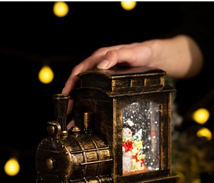 Close-up of vintage bronze train snow globe with snowman figurine and festive lighting
