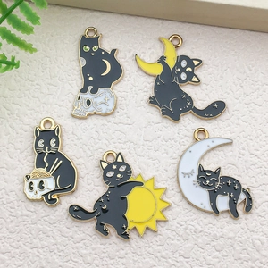 Detail of five creative black cat enamel charms with gold edges and various cartoon poses