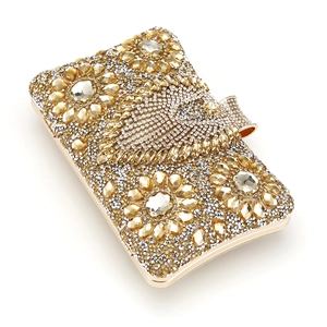 Macro shot of gold evening clutch bag with intricate crystal flower and wing patterns