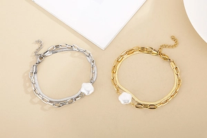 Detail of layered gold and silver snake chains with floral pearl pendants and lobster clasp