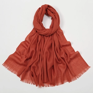Detailed view of the wrinkled texture and fringe edges on a reddish-brown cotton scarf