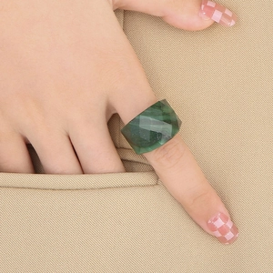 Close-up of emerald green faceted statement ring with 18K gold plating on model