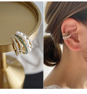 Detailed view of layered gold ear cuff with pearls and green zircon on ear