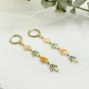 Close-up of colorful mushroom tassel earrings with gold-plated steel on a white plate
