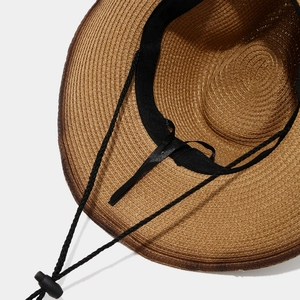 Close-up of woven straw cowboy hat interior with sweatband and adjustable wind rope