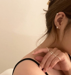 Detail of 925 sterling silver ear cuffs and minimalist stackable rings worn by a model
