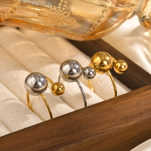 Detail of adjustable titanium steel rings with gold and silver beads on satin fabric