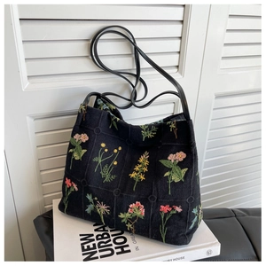 Detailed embroidery on a black tote bag showing colorful floral patterns and texture