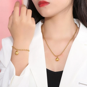 Elegant gold beaded chain necklace and bracelet set with round pendant on female model
