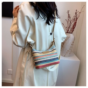 Detail of colorful woven straw bag featuring vibrant stripes and brown leather strap