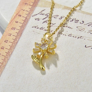 Detail of sunflower pendant with cubic zirconia on gold chain with vintage props