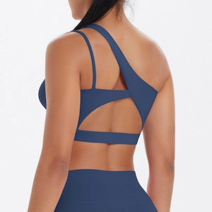 Macro detail of navy blue sports bra with irregular one-shoulder and criss-cross back straps