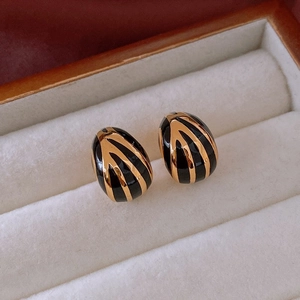 Vue détaillée de boucles d'oreilles ovales vintage en émail noir et texture dorée