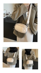 Detail of off-white camera bag featuring lychee texture and dual zipper compartments