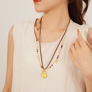 Detail of double-layer necklace with heart lock and key charms on brown leather cord