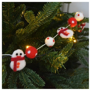 Detail of handmade wool felt snowman and pom-poms on a Christmas tree with warm lights