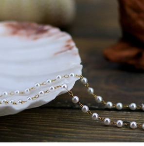 Macro detail of elegant white pearls and delicate golden chain on a shell background