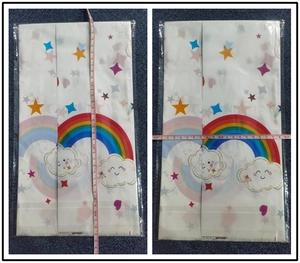 Detailed dimensions of rainbow cloud plastic tablecloth with tape measure on blue carpet