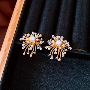 Macro shot of 18k gold plated firework stud earrings with pearls and white zircons