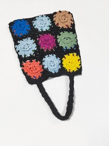 Detailed view of colorful 3D crochet flower patterns on a black handmade woven tote bag