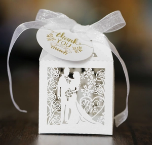 Detail of white laser-cut wedding candy box with groom, bride and thank you tag