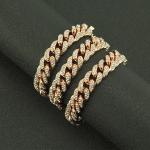 Macro shot of three rose gold Cuban link bracelets with full diamond pavé on black background