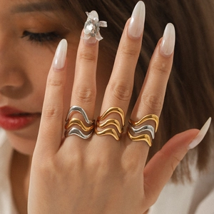 Detail of stacked wave rings in gold and silver finish on model hand