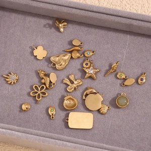 Detailed view of gold plated sea charms with colorful zircons on a gray tray