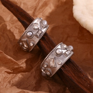 Macro shot of silver vintage-style rings with embedded pearls and diamonds on textured metal