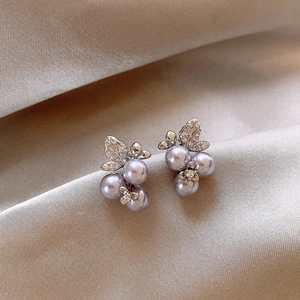 Macro shot of silver flower earrings with purple pearls and rhinestones on satin