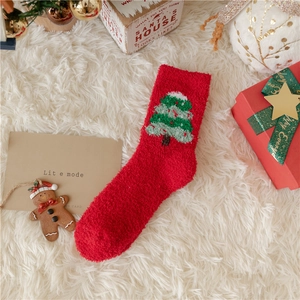 Detailed view of plush red Christmas sock with green tree pattern on soft white carpet