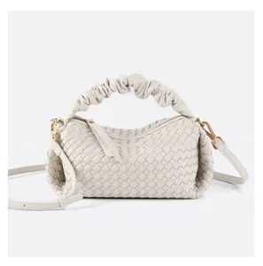 Detailed view of woven soft leather handbag with ruffled handle and golden hardware