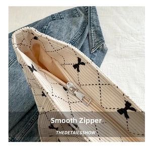 Detail view of corduroy tote bag with black bow patterns and a smooth silver metal zipper