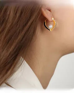 Detailed view of hollow heart pearl earrings with sparkling micro-pave cubic zirconia on ear