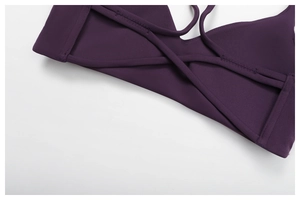Detail of dark purple yoga top featuring cross-back straps and high-elastic fabric