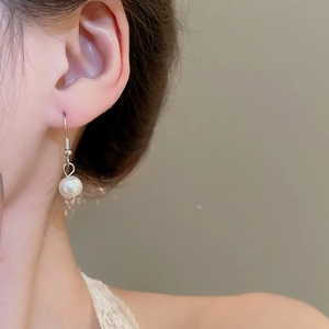 Elegant white round pearl hook earrings worn by a model in a natural soft lighting