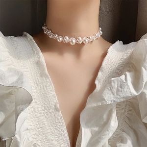 Close-up of elegant woven pearl necklace with alternating sizes on model neck
