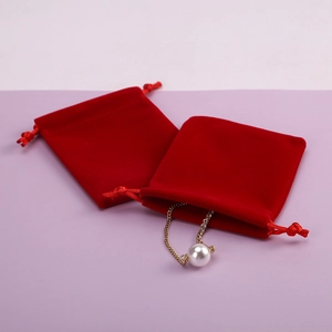 Close-up of red velvet jewelry pouches with drawstring and elegant pearl necklace