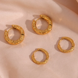 Detailed view of gold hammered texture hoop earrings on elegant pink silk fabric