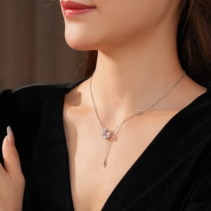Gros plan d'un collier croix en argent avec pendentif gemme rose porté par un mannequin