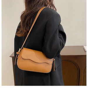 Detailed side view of a brown minimalist leather crossbody bag with an adjustable strap