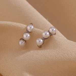 Detailed close-up of three white pearls in a vertical curve on a silver metal stud