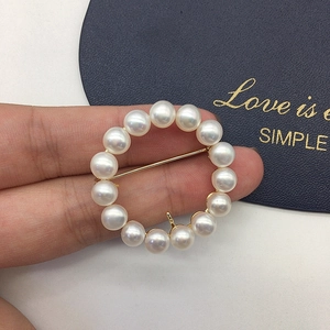 Detail of elegant wreath brooch featuring 14 white freshwater pearls and golden pins